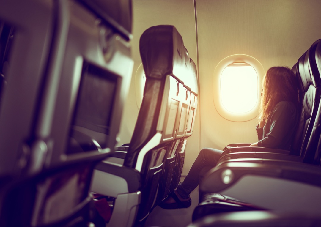 A traveller settled into a window seat, watching the sunset glow through the cabin window